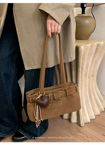 Detail of retro brown matte shoulder bag featuring heart charm and woven tassel accent
