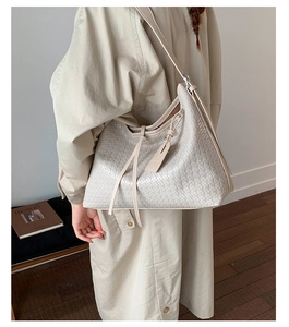 Détail du sac hobo tissé beige avec décoration de glands et fine bandoulière en cuir