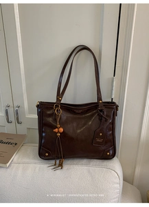 Close-up of vintage brown tote bag featuring gold hardware and wooden bead tassel detail