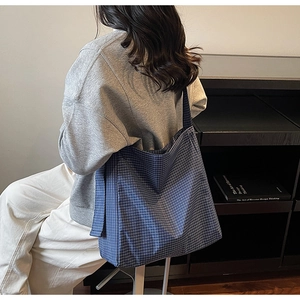 Detailed side view of large blue and white plaid oxford fabric tote bag worn on shoulder