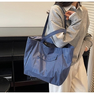 Detailed shot of a blue checkered nylon tote bag featuring a practical front flap pocket