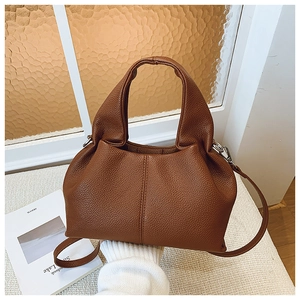Détail du sac seau en cuir grainé marron avec poignée et bandoulière réglable