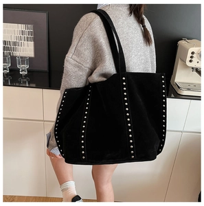 Détail du grand sac cabas en daim noir avec clous argentés porté par un modèle