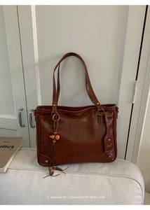 Close-up of deep brown vintage oil-wax leather tote bag with wooden bead fringe detail