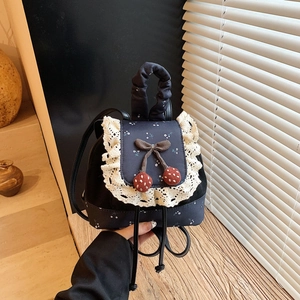 Détail du mini sac à dos bleu avec bordure en dentelle blanche et cerise décorative