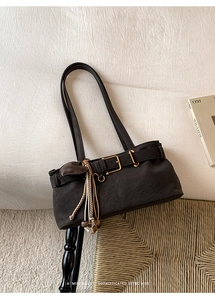 Retro dark brown crossbody bag with woven tassel and metal buckle on linen background