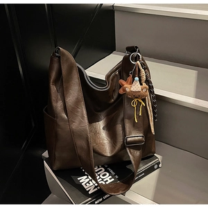 Detail of dark brown tote bag featuring matte faux leather and a cute bear charm