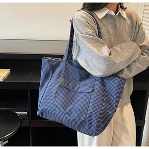Detail of blue plaid tote bag featuring a practical front flap pocket and woven texture