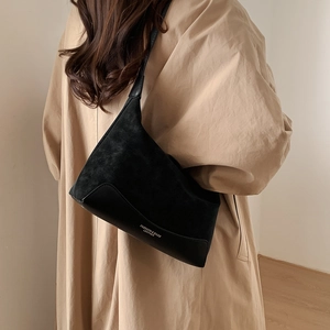 Detail of black leather and suede shoulder bag with FASHION & BAGS logo on a model