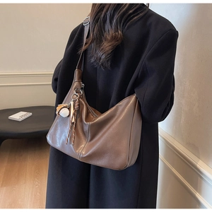 Detail of a deep brown leather hobo bag showing soft texture and baseball charms