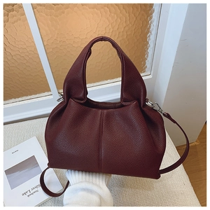 Détail du sac seau bordeaux avec texture cuir grainé et finitions métalliques argentées