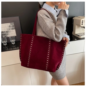 Détail du sac cabas en daim bordeaux avec rivets argentés et design bandoulière spacieux