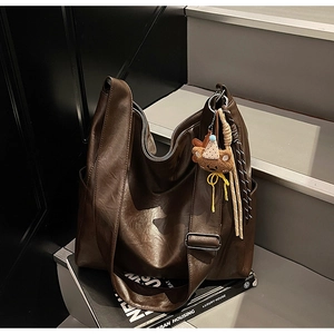 Detail of coffee brown PU leather tote bag with wide strap and plush bear charm