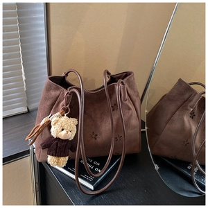 Sac fourre-tout en daim marron avec découpes florales et breloque ours dans un décor de maison