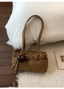 Detailed close-up of retro brown shoulder bag with leather belt buckle and heart charm