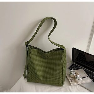 Detailed shot of green plaid canvas tote bag with adjustable strap on a white office desk