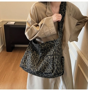 Leopard print canvas messenger bag with wide shoulder strap shown on a model for scale