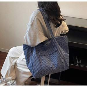 Side view of blue and white checkered tote bag with wide strap and front pocket