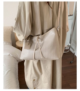 Gros plan détaillé de la texture tissée du sac fourre-tout beige au design épuré à cordon