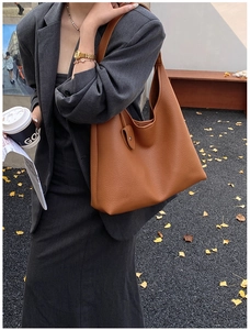 Detailed texture of caramel brown lychee leather tote bag shown in outdoor setting