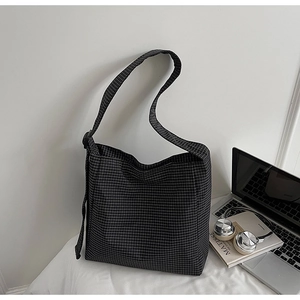 Detail of checkered tote bag side buckle and strap against minimalist room background