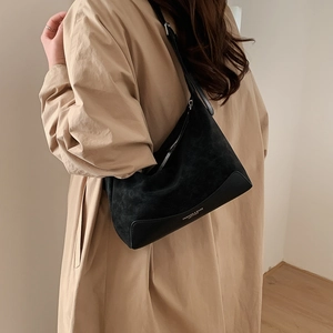 Detail of black suede and leather hobo bag with white printed logo shown on shoulder
