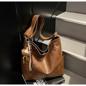 Close-up of brown PU leather hobo bag with a cute plush bear charm and vintage texture