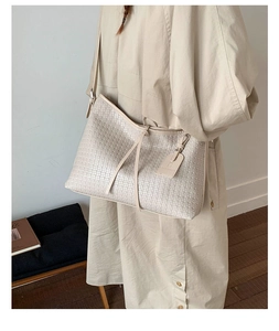 Détail du cuir tressé d'un sac cabas beige avec son étiquette décorative chic
