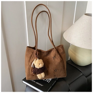 Détail du sac cabas mat marron foncé avec découpes florales et breloque ourson