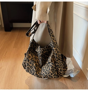 Detail of leopard print canvas tote bag with functional utility pockets and long shoulder strap
