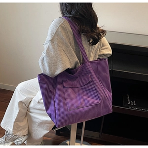 Detail of purple plaid tote bag showing the front pocket flap and woven fabric texture