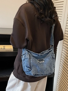 Sac à bandoulière en denim avec design multi-poches et logo métallique porté par un modèle