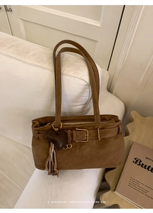 Close-up of retro brown handbag with heart pendant and woven tassel on white sofa