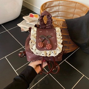 Détail d'un mini sac à dos marron vintage avec dentelle et broderie de cerises