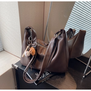Detail of dark brown leather tote bag with white contrast stitching and baseball charm