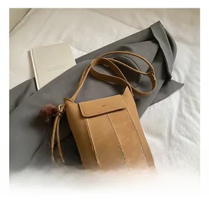 Dettaglio borsa a secchiello marrone vintage con nappa decorativa e pompon di peluche