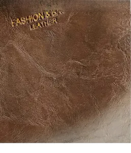 Macro detail of textured dark brown leather with FASHION & BAGS gold embossed lettering