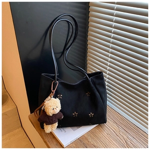 Détail du sac bandoulière en daim noir avec motif floral ajouré et pendentif ours mignon