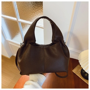 Détail d'un sac à main en cuir grainé marron foncé avec structure hobo et bandoulière