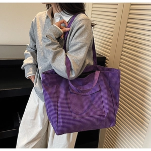 Close-up of purple plaid canvas tote bag with large front pocket and long shoulder strap