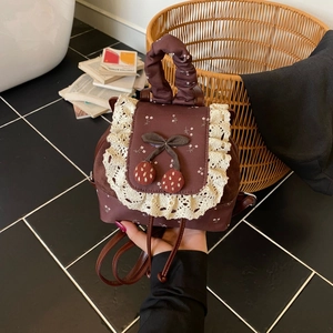 Détails d'un mini sac à dos vintage avec bordure en dentelle et breloques de baies