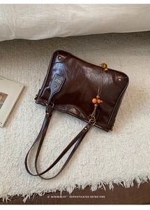 Detail of dark brown retro shoulder bag with gold studs and wooden bead ornament