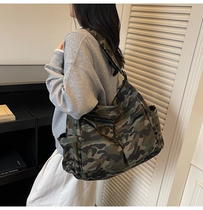 Detailed side view of large camo canvas crossbody bag with multiple external pockets