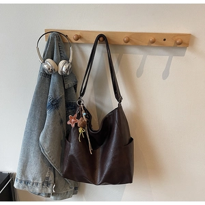 Close-up of dark brown tote bag on hanger with decorative star and bear charms