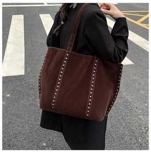 Détail du sac cabas en daim marron foncé avec clous argentés et large bandoulière