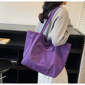 Detail of purple plaid tote bag with front flap pocket worn by model on shoulder