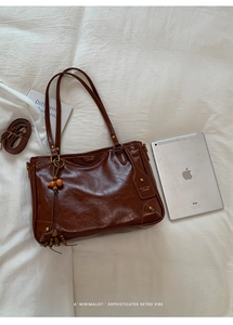 Detail of vintage brown tote bag with wooden bead charm and detachable shoulder strap