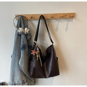 Detail of dark brown faux leather tote bag with star charm hanging on wooden rack