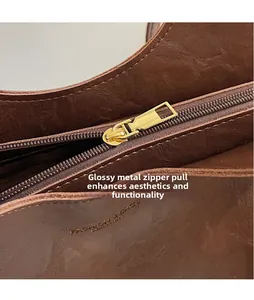 Close-up of golden zipper hardware and wax-textured brown leather bag surface