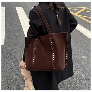 Détail d'un grand sac cabas en daim marron foncé avec des rivets métalliques argentés